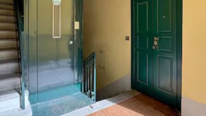 Un pasillo con una puerta verde, una escalera y un escalón pequeño que lleva a la puerta.