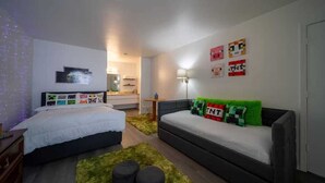 A bedroom with a bed, a sofa, a small table, and a wall-mounted TV.