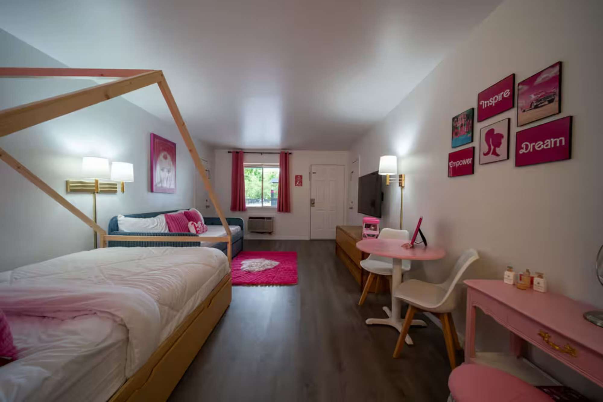 Et soveværelse med himmelseng, et skrivebord med stol, en sofa og et fjernsyn.