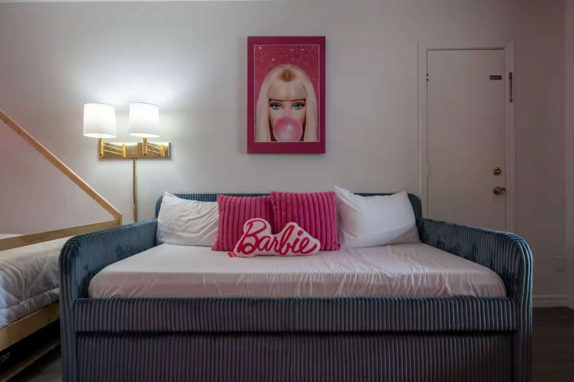 A bedroom with a bed, a bedside lamp, a door, and a framed picture on the wall.