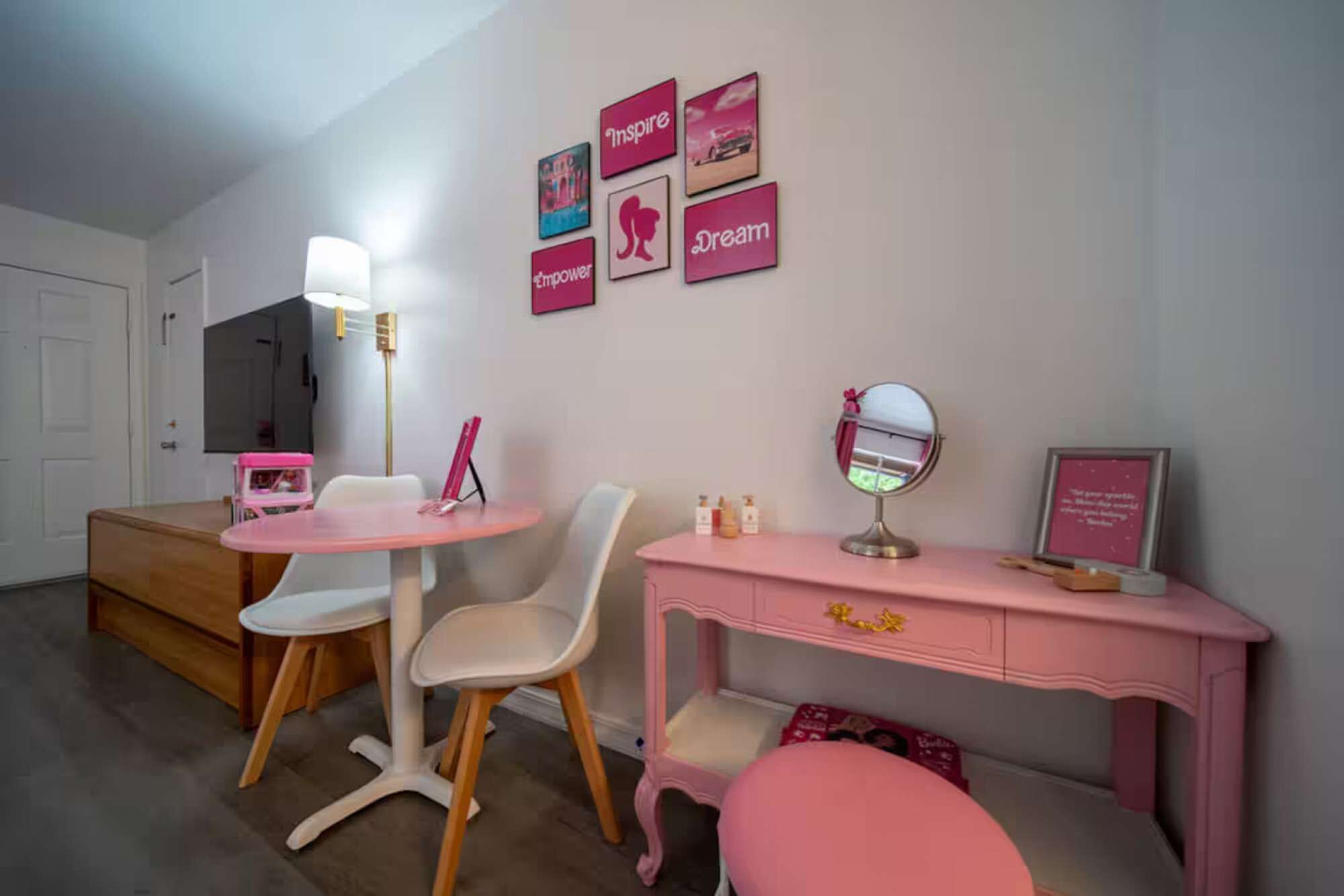 A bedroom with a bed, a desk with a mirror, a chair, a dresser, and a vanity table.