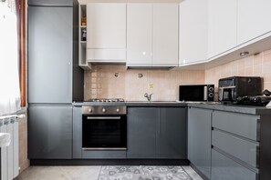 Une cuisine moderne avec des meubles gris, un four encastré, un four à micro-ondes et une cuisinière à gaz.