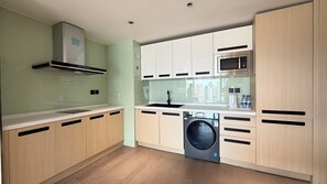 A modern kitchen with a built-in washing machine, a microwave, and a window overlooking a cityscape. - BeijingSanlitunShimao Int'l Serviced Apt (Beijing)
