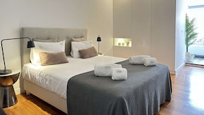 Un dormitorio moderno con cama, lámparas de noche, mesitas de noche y una ventana con vistas.