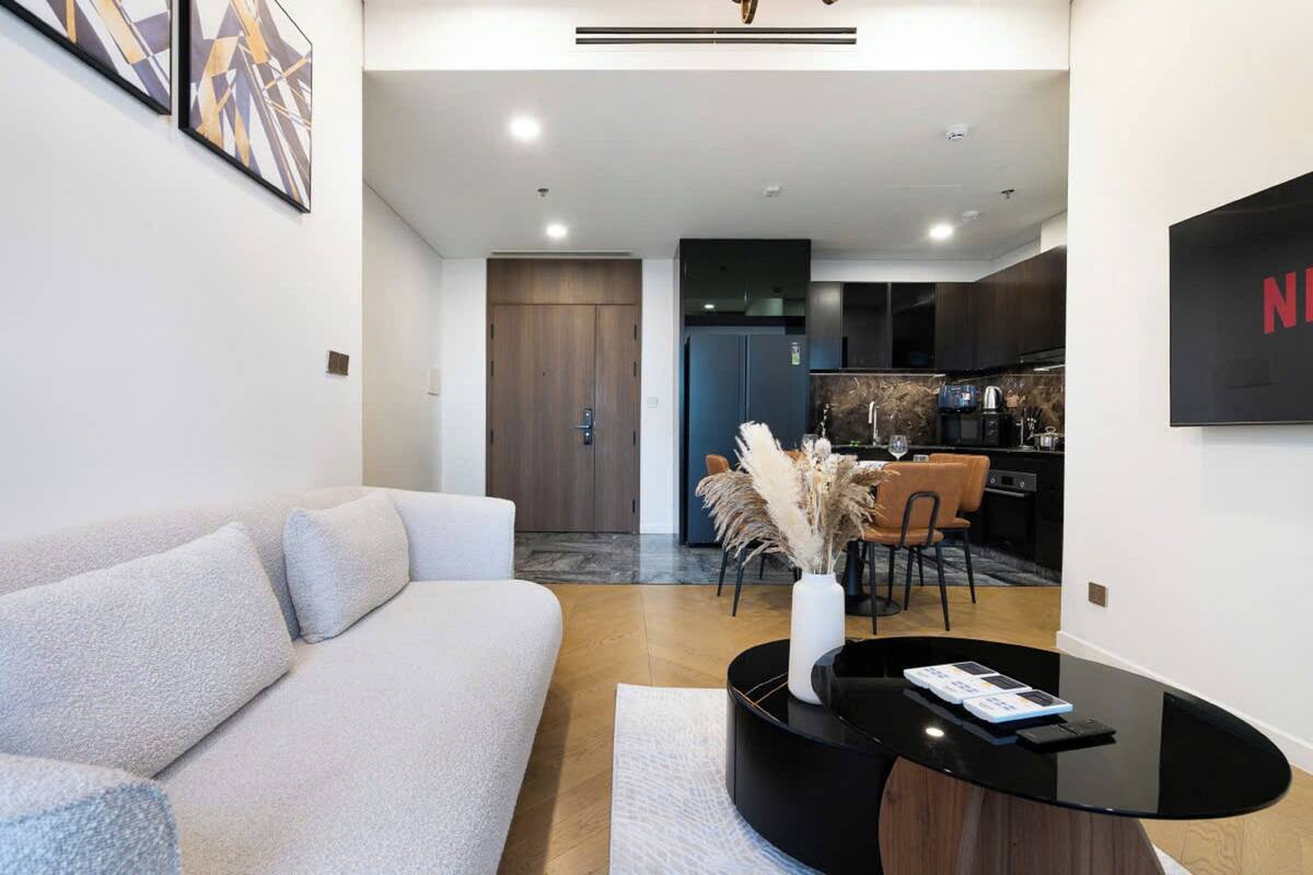A modern living room with a sofa, a coffee table, and a dining area with chairs and a vase of pampas grass.
