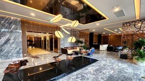 Un lobby moderno con piso de mármol, mostrador de recepción, zona de estar y un amplio panel de vidrio.