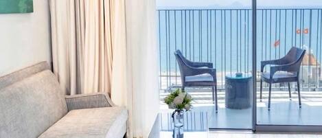 A modern living room with a sofa, a coffee table, and a balcony with two chairs and a small table.