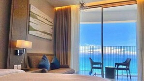Ein Hotelzimmer mit einem großen Bett, einem Schreibtisch, einem Stuhl und einem Balkon mit Meerblick.