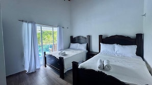 Ein Zimmer mit zwei Betten, einem Balkon und Blick auf Grünflächen.
