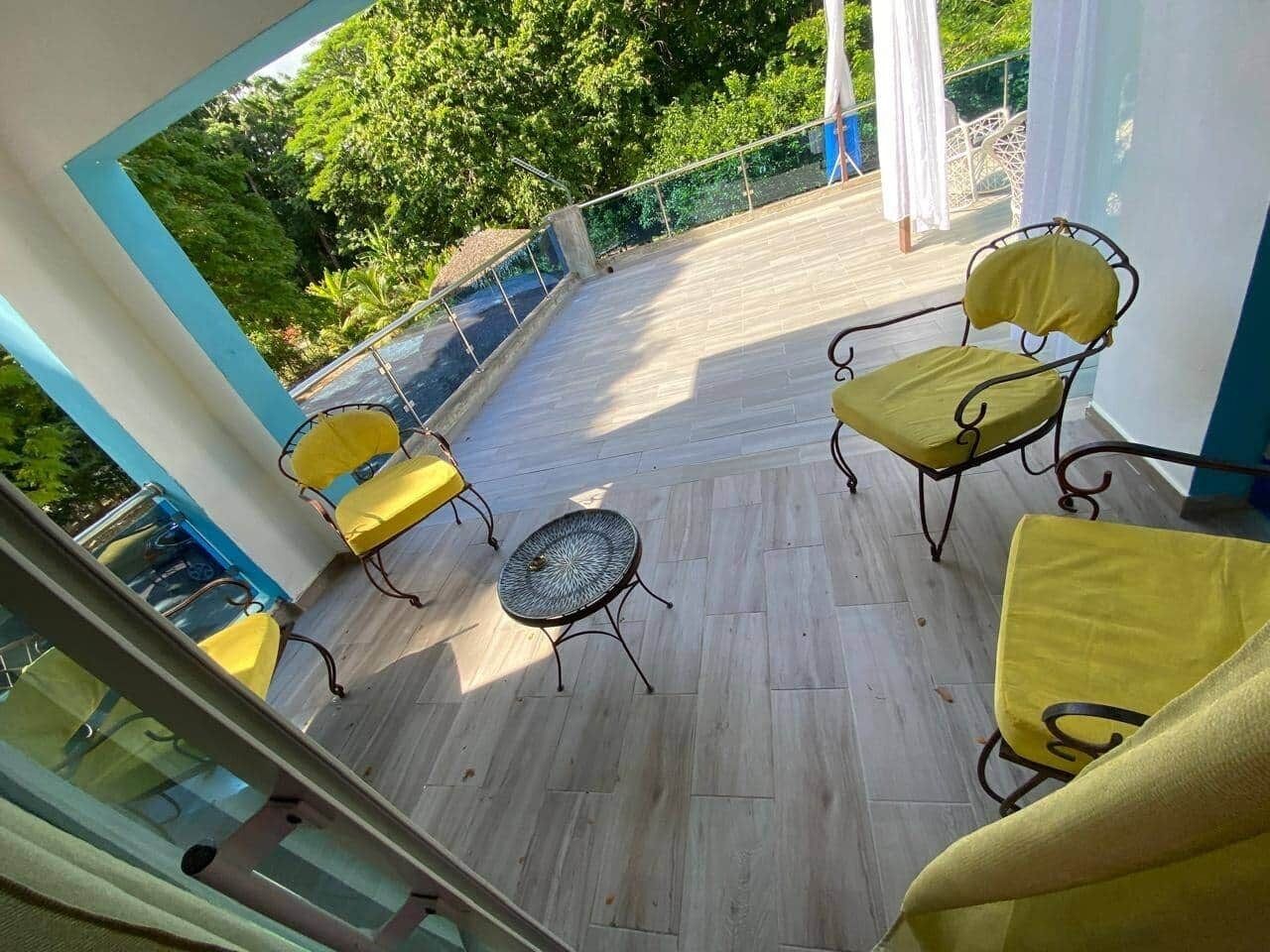 A balcony with yellow chairs and a small round table.
