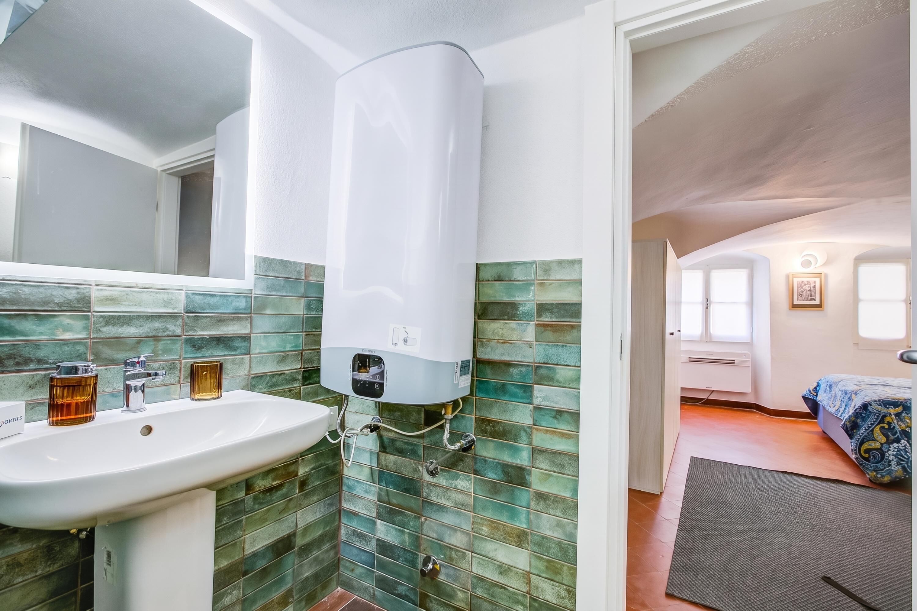 Une salle de bain avec un lavabo blanc, un bocal en verre et un chauffe-eau blanc.