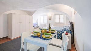 A compact room with a dining table set for two, a bed with a patterned bedspread, a television, and a wardrobe. - Casa Vacanze Maimone 3 Central Sanremo Old Town (Sanremo)