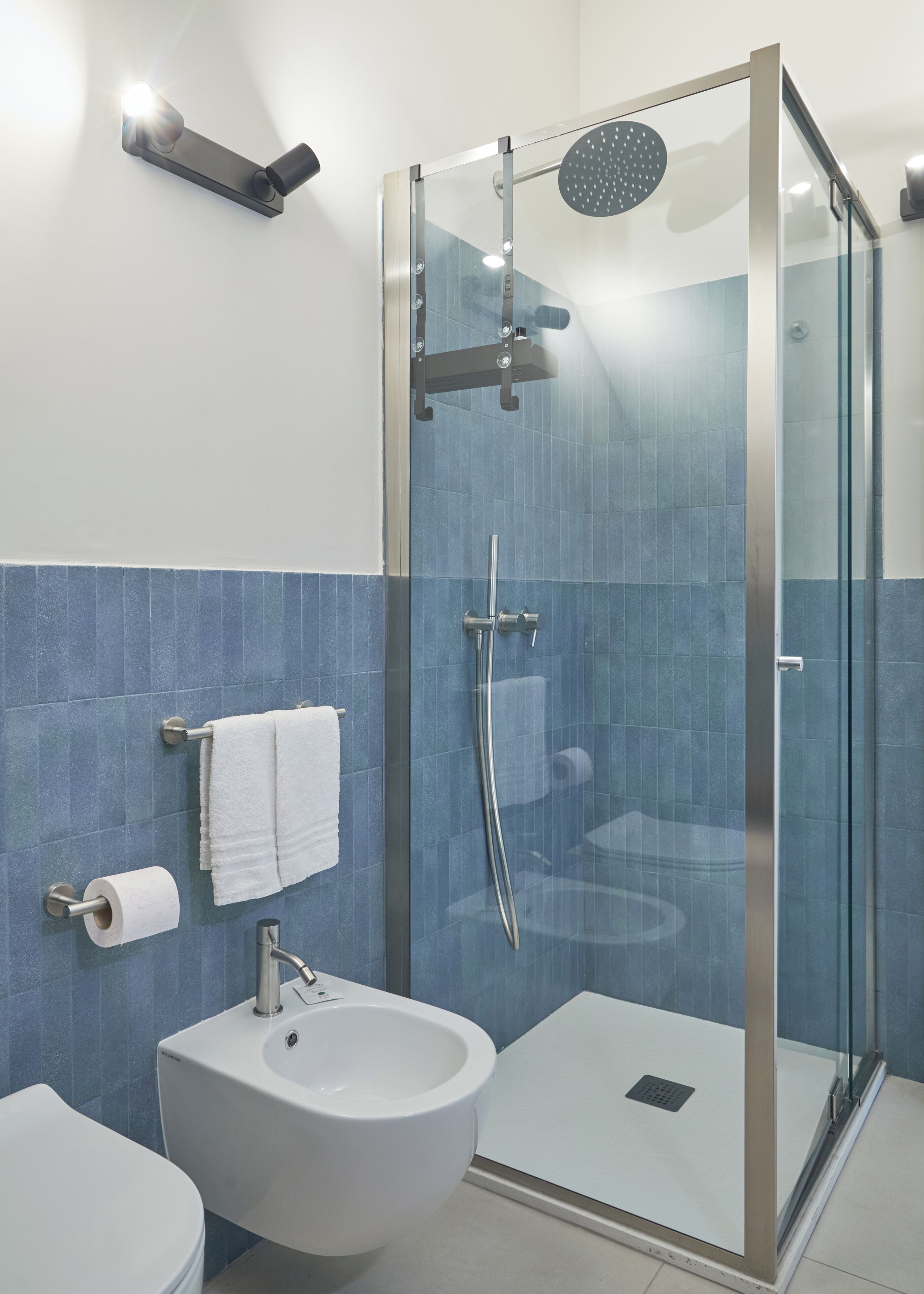 A modern bathroom with a glass-enclosed shower, a white sink, and a towel rack.