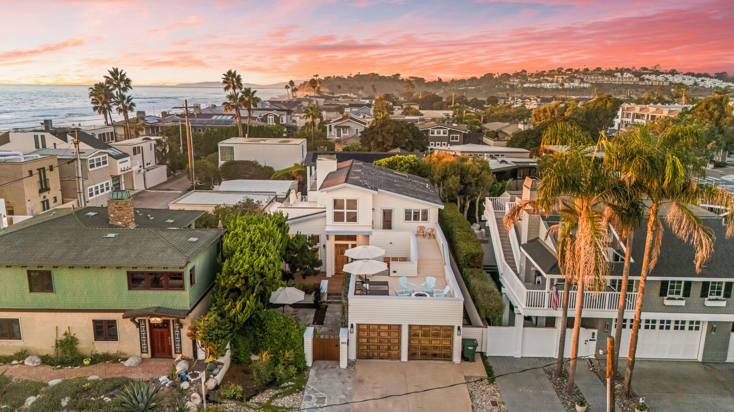 A residential area with houses, a view of the ocean, and palm trees.