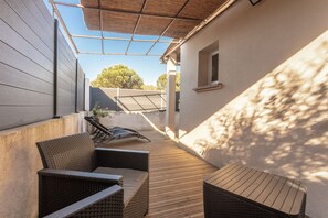 A covered outdoor patio with wicker furniture, a table, and a view of the surrounding area.