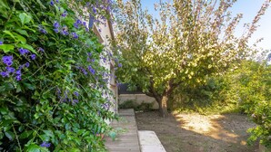 A garden pathway leading to a building, surrounded by lush greenery and flowering plants. - Apartment 'Les Sables' with Private Terrace, Wi-Fi and Air Conditioning (Bormes-les-Mimosas)