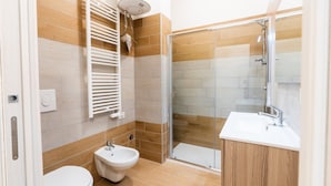 Un bany modern amb vàter, bidet, dutxa i rentapisa.