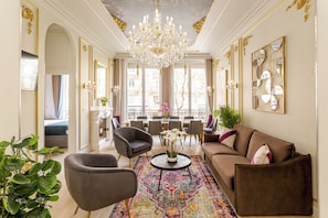 Un salon luxueux agrémenté d’un lustre, de canapés, de fauteuils et d’un coin repas offrant une vue imprenable.