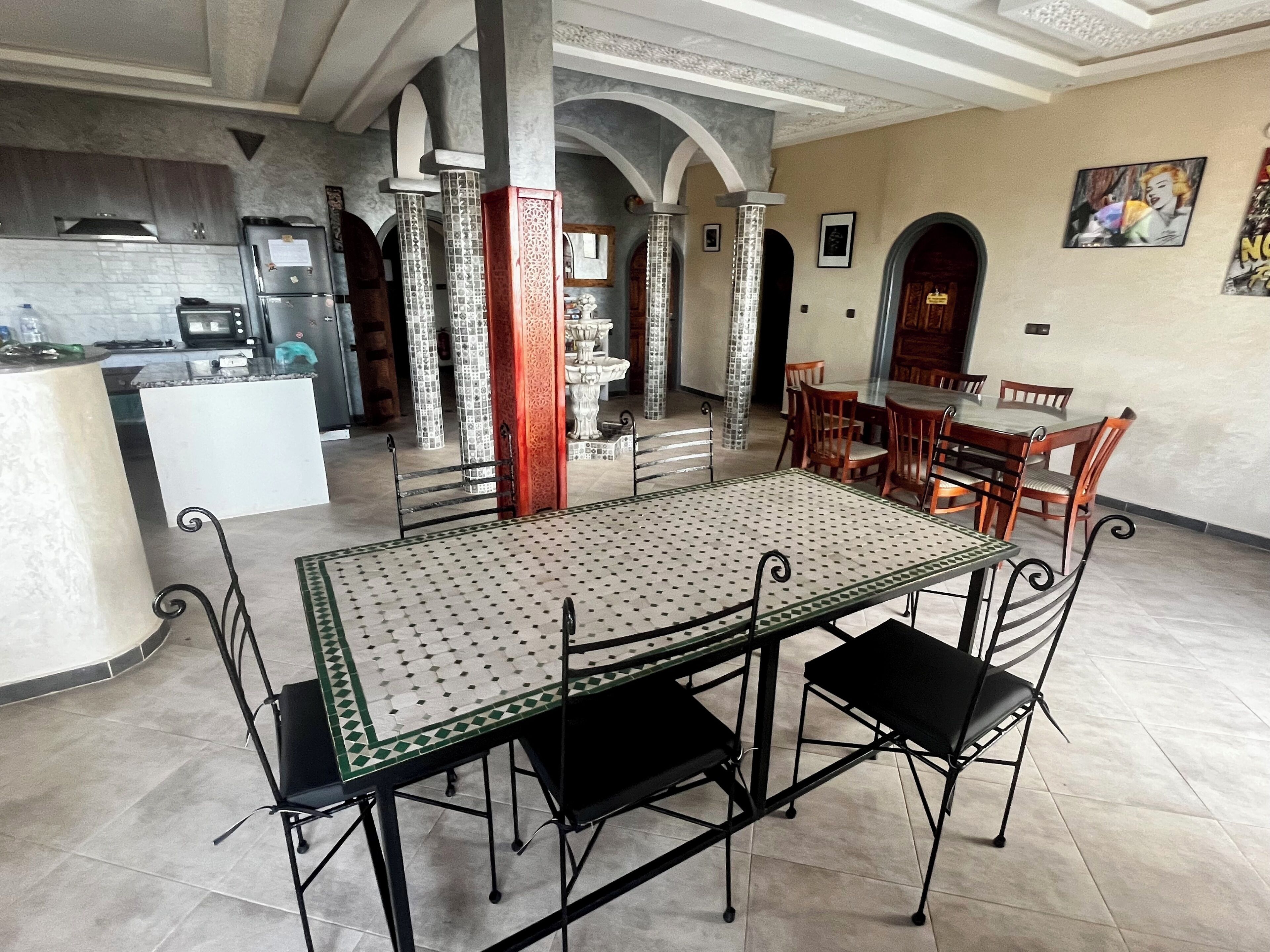 A spacious kitchen with modern appliances, a dining area with a patterned table and chairs, and a decorative fountain.