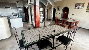 A spacious kitchen with modern appliances, a dining area with a patterned table and chairs, and a decorative fountain.