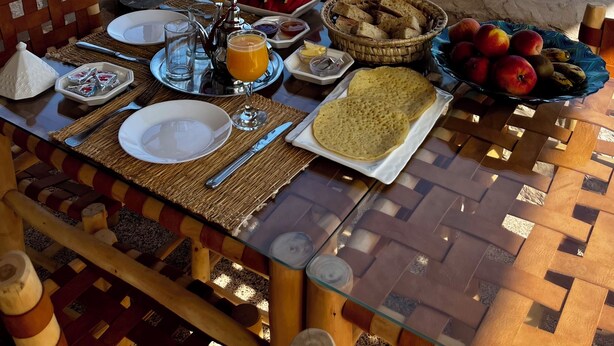 Een eettafel met ontbijtartikelen en uitzicht op een zwembad en de oceaan.