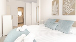 Une chambre d’hôtel moderne avec un grand lit, une armoire, un miroir et des œuvres d’art accrochées aux murs.