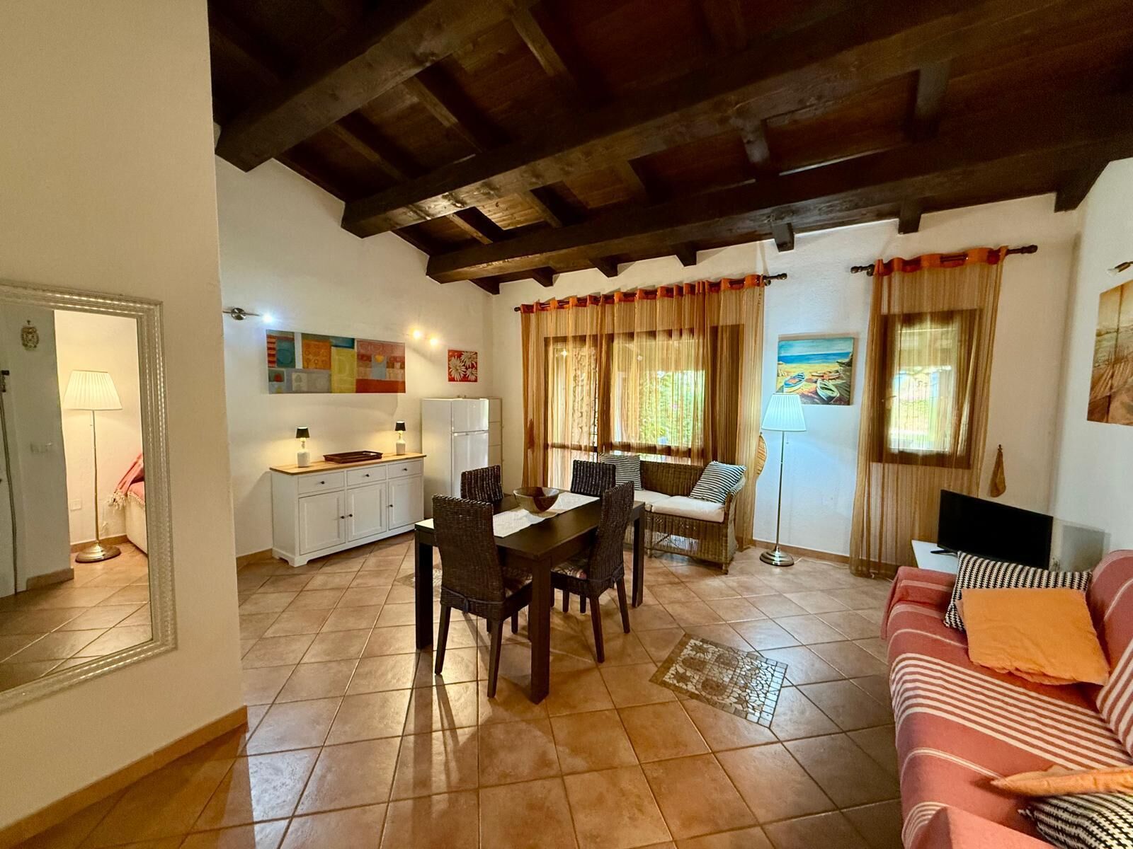 A cozy living room with a dining area, a sofa, and a kitchen in the background.