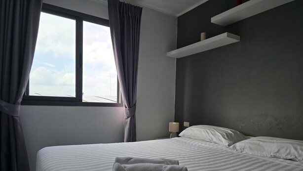 Une chambre d’hôtel avec un grand lit, une table de chevet, une lampe et une fenêtre avec des rideaux.
