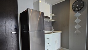 Une cuisine moderne avec un réfrigérateur en acier inoxydable, des armoires blanches et une horloge murale.