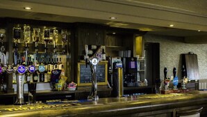 Een bar met verschillende biertappen, een krijtbordmenu en een verscheidenheid aan flessen op planken.