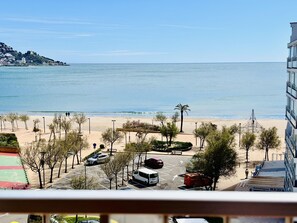 A coastal view with a beach, parked cars, and a building with a sign 'boutique RED'. - Vintage Beachfront Apartment - Santa Margarita (Roses)