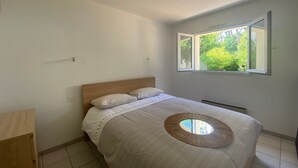 Un dormitorio con cama, ventana y vista a zonas verdes.