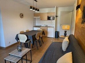 Ein kompakter Wohnbereich mit Essplatz, Küchenzeile und einer Couch.