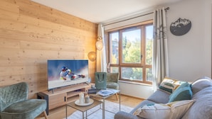 Una sala de estar moderna con una pared de madera, un ventanal grande, un sofá, un televisor y una silla.