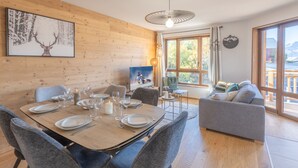 Un comedor con una mesa de madera dispuesta para cuatro personas, sillas tapizadas de color gris y un cuadro de un ciervo en la pared.