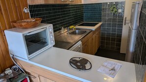 Kompakti keittiö, jossa on mikroaaltouuni, pesuallas ja puiset kaapit.