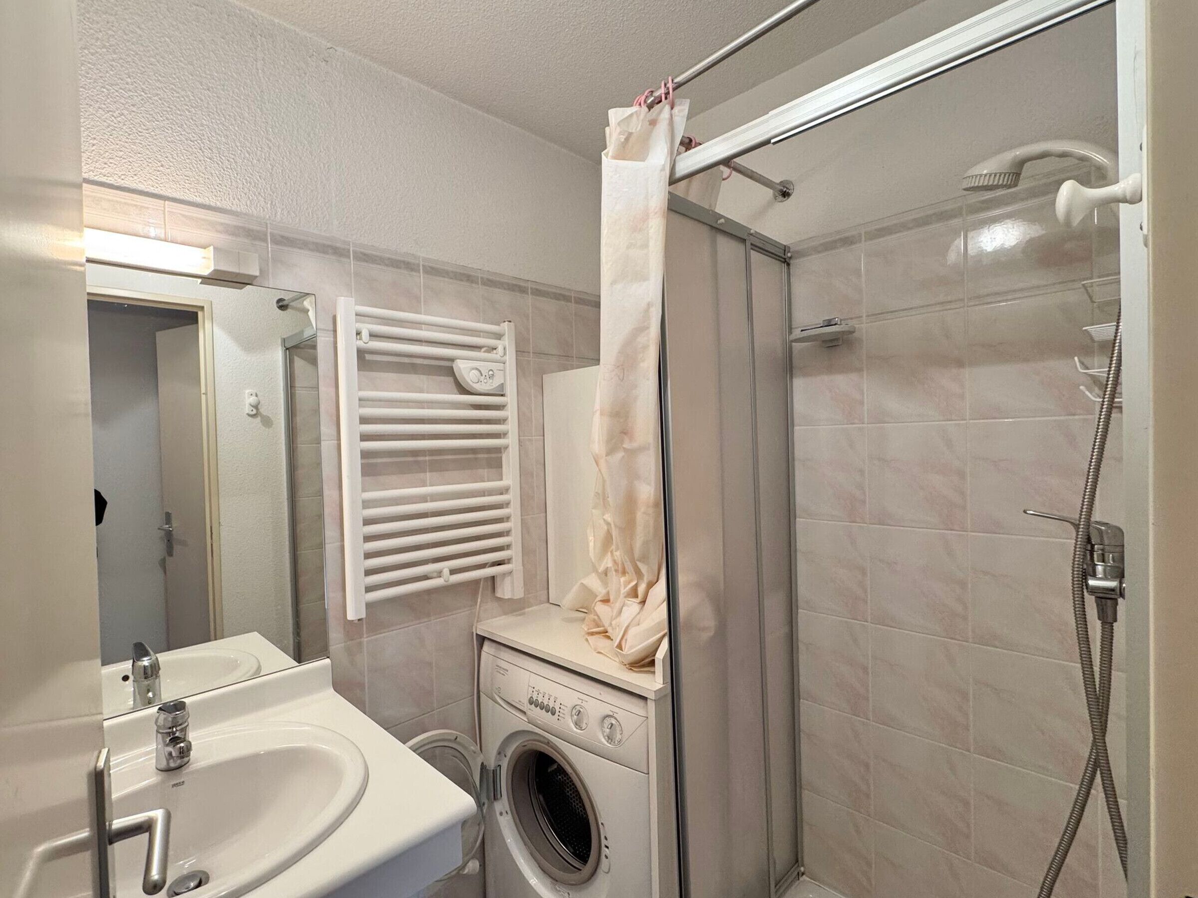 Ein Badezimmer mit Waschbecken, Waschmaschine und Dusche.