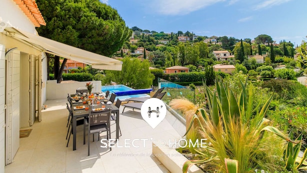 Eine Terrasse mit Esstisch, Stühlen und Pool.