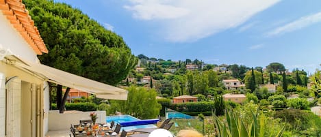 Um terraço com mesa de jantar, cadeiras e piscina.