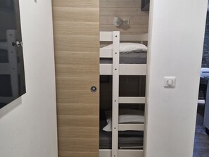 A bunk bed with a wooden door and a light switch on the wall.