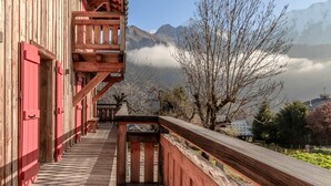 A wooden balcony with a view of mountains and a clear sky.