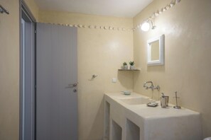 A bathroom with a white sink, mirror, and two small potted plants on a shelf.
