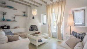 Una sala de estar acogedora con chimenea, muebles blancos y objetos decorativos en estanterías.