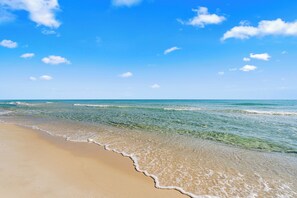 Une plage avec une eau d’un bleu limpide et un rivage sablonneux.