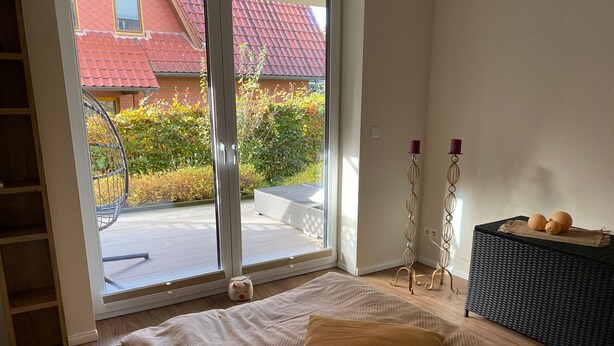 Ein Schlafzimmer mit einem Bett, einem Fenster, einem kleinen Tisch mit Dekoration und einem Korbtisch.