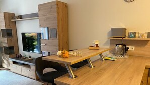 Eine moderne Küche mit Holzausstattung, einem integrierten Fernseher und einer Kaffeemaschine auf der Arbeitsfläche.