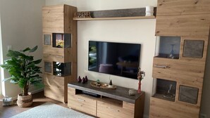 Ein modernes Wohnzimmer mit einem großen Flachbildfernseher, der an einer Holzwand angebracht ist.