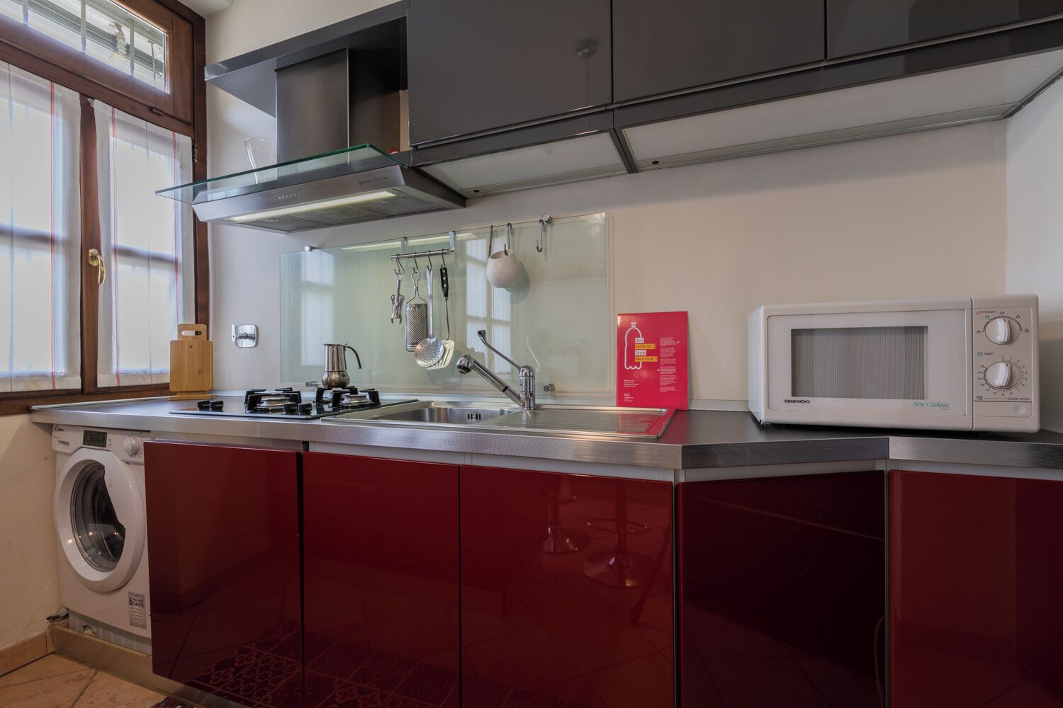 A compact kitchen with a built-in washing machine, a microwave, and a gas stove.