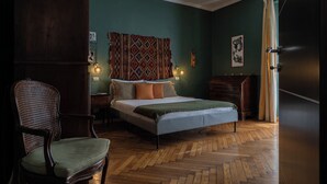 Quarto com cama, cadeira, cômoda e parede com tapeçaria estampada.