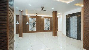 Un hall espacioso con techo alto, iluminación empotrada, ventilador de techo y suelo de baldosas pulidas.